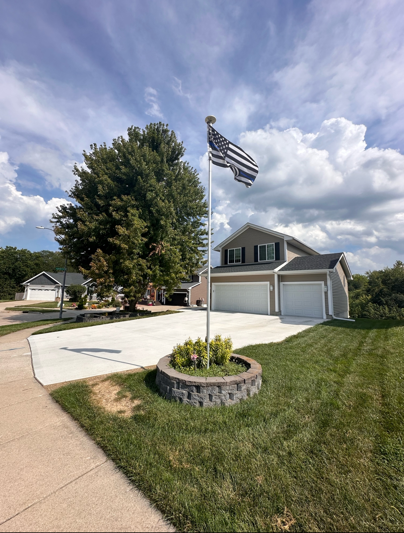 American flag waving proudly in front of a Des Moines home with a new concrete driveway. Concrete services Des Moines.