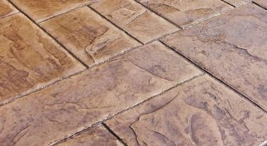 Stamped concrete Des Moines patio with a textured stone pattern and dark grout lines.