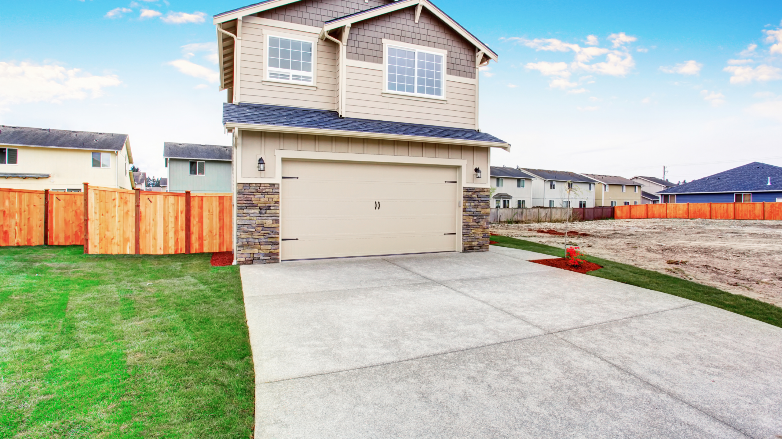 Concrete driveway in front of a beige house, illustrating when to replace a driveway.
