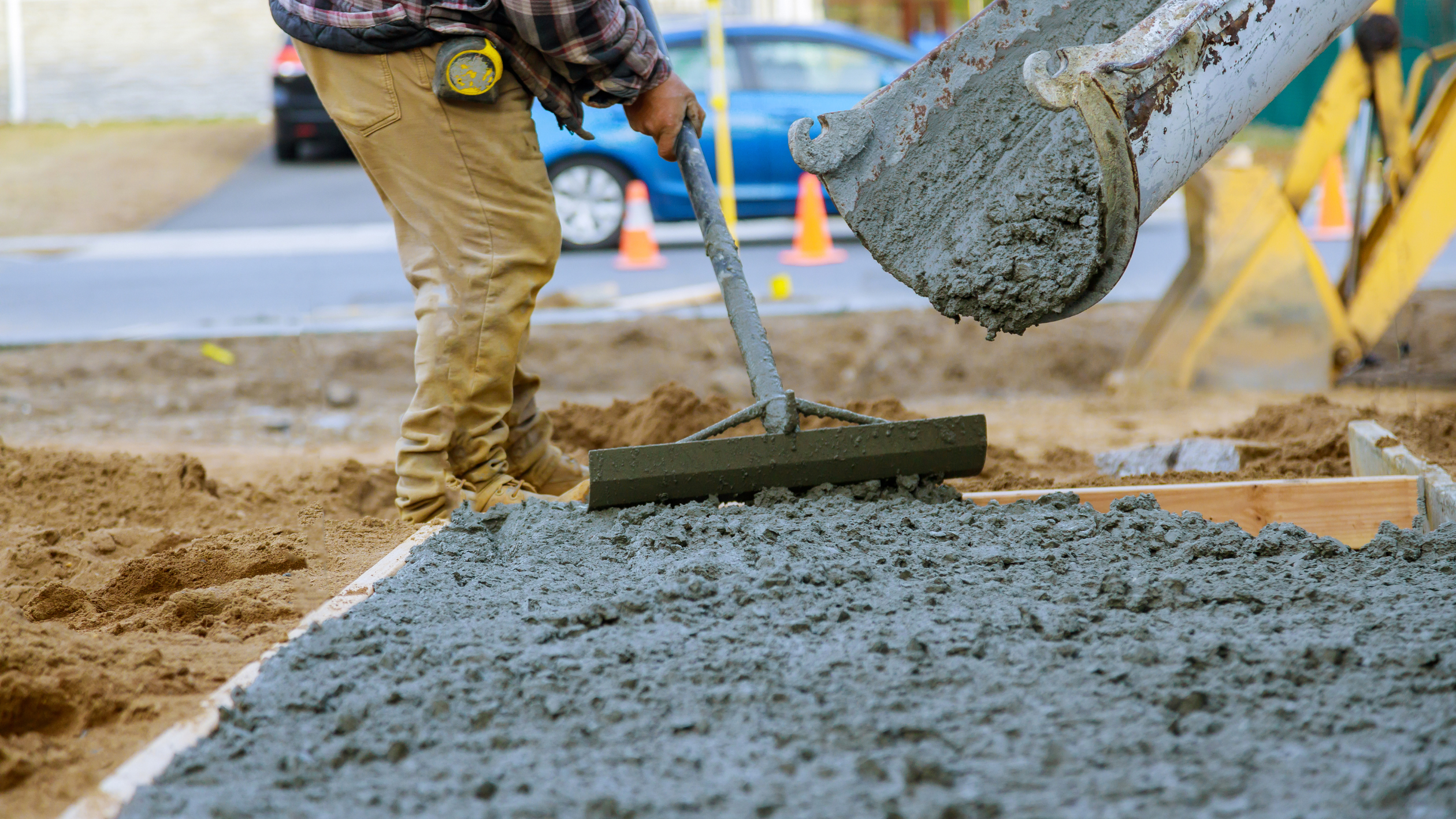Worker spreading wet concrete from a chute during construction