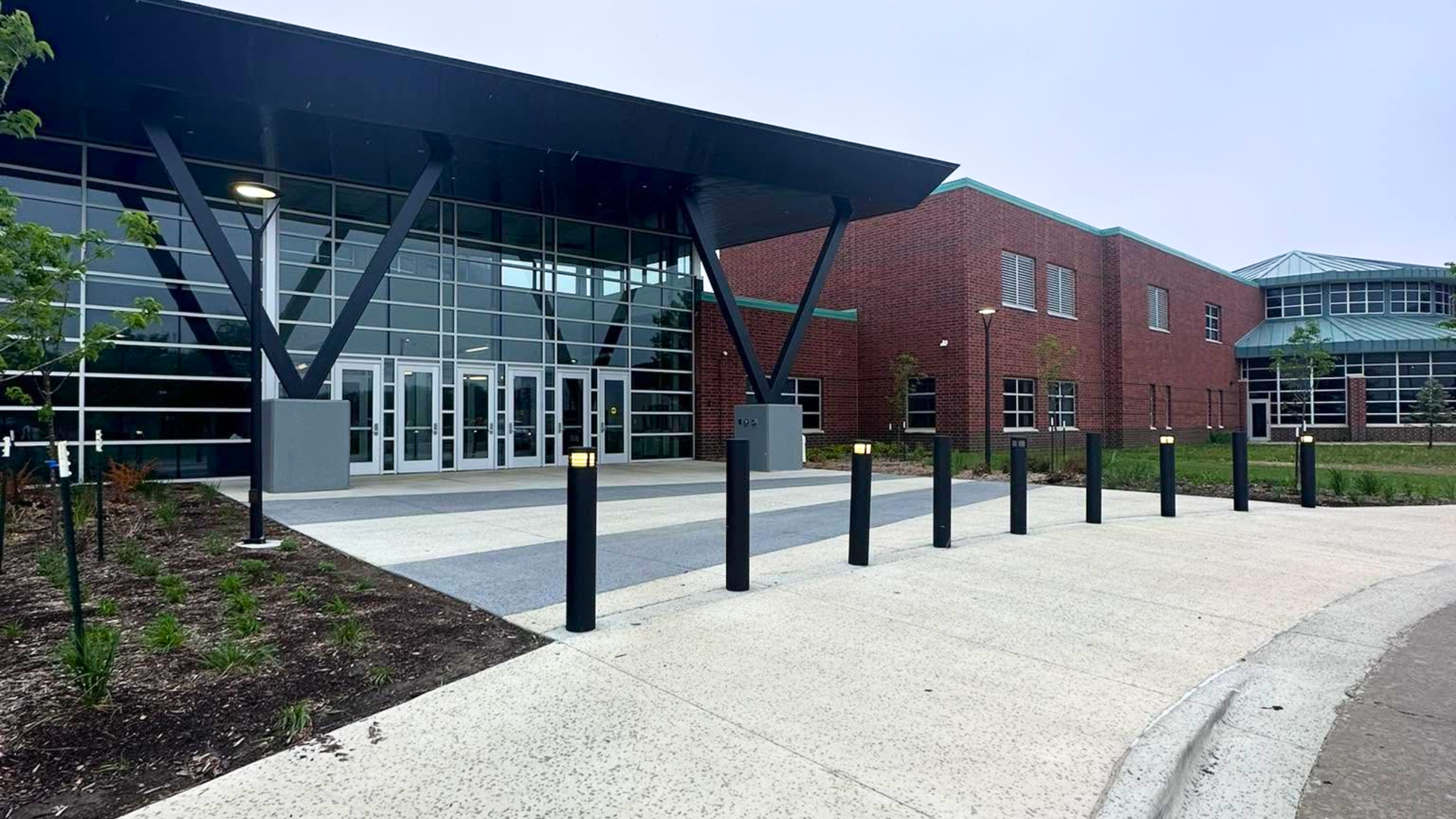 Modern brick building entrance with concrete walkway and bollard lighting