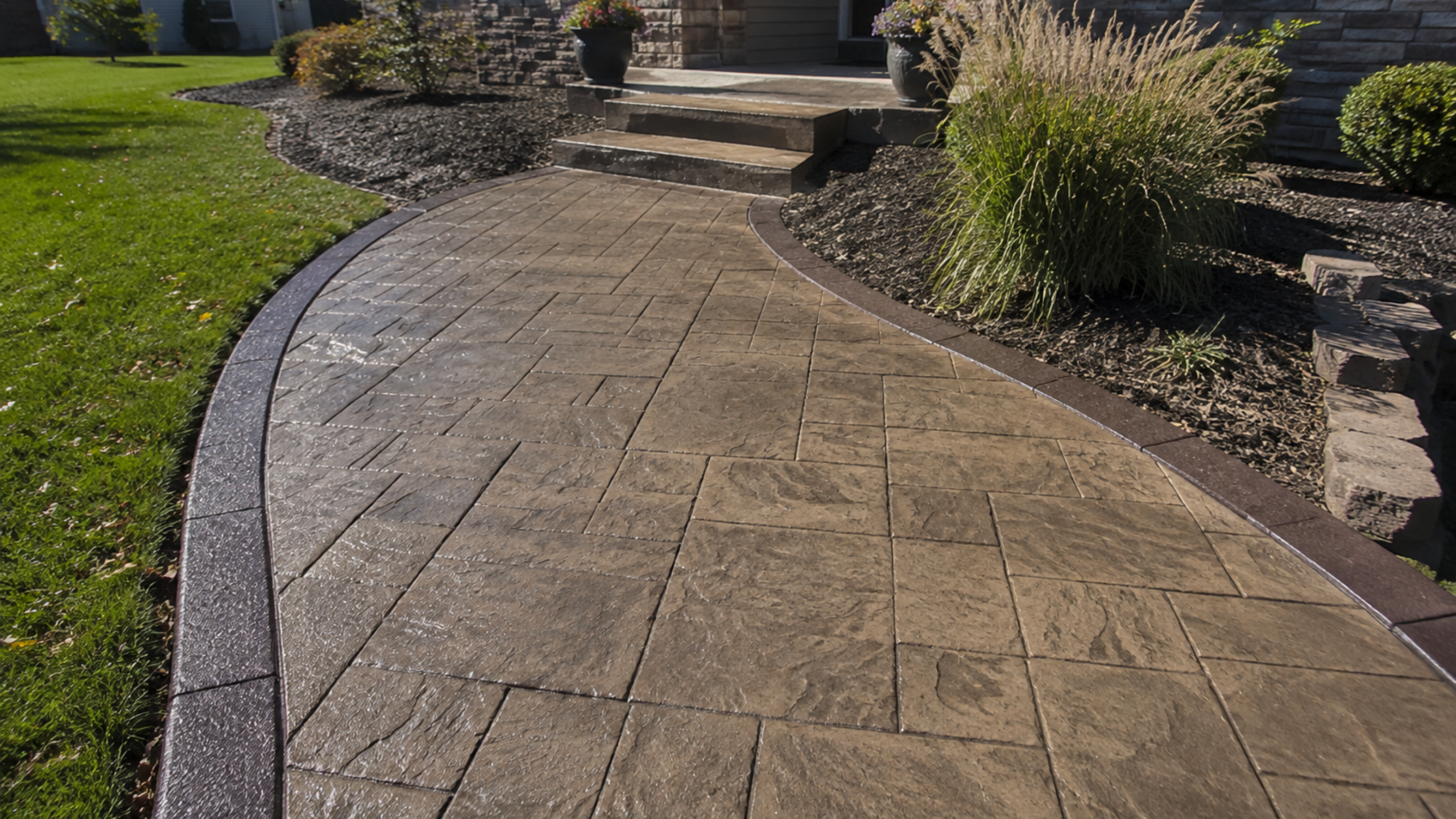 Stamped concrete walkway with dark border leading to house steps in Des Moines
