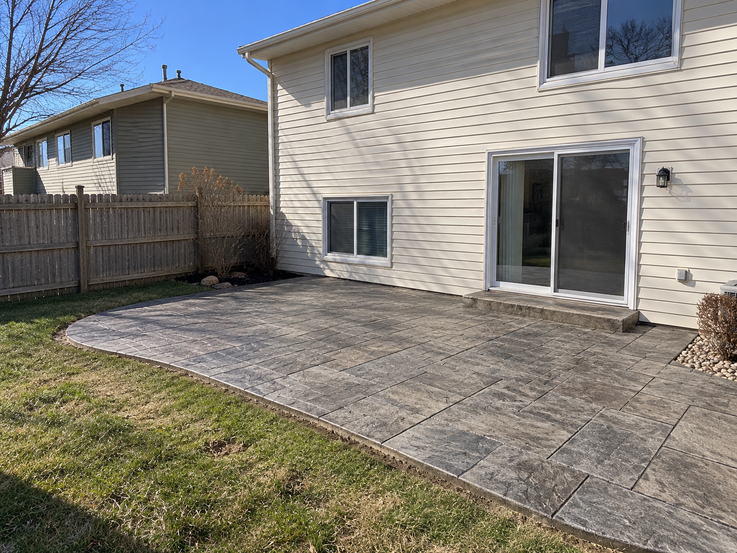 Stamped concrete patio in a backyard, showcasing a textured pattern.